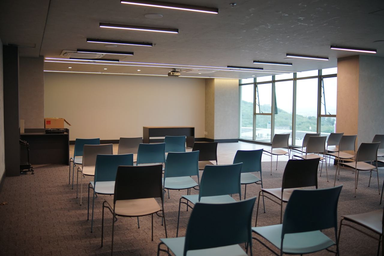 Sala de treinamento com cadeiras, projetor e janelas amplas com vista para a serra